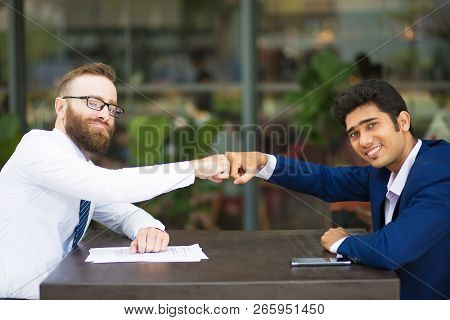 Cheerful Business Partners Making Fist Bump As Symbol Of Teamwork. Positive Multi-ethnic Business Co
