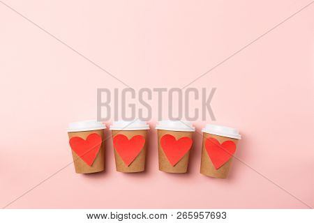 Row Of Four Brown Craft Cups Of Coffee Or Tea To Go On The Pastel Pink Background. Flat-lay, Top-vie