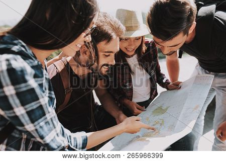 Group Of Young Smiling People Holding Paper Map. Casualy Dressed Happy Travelers With Backpacks Plan