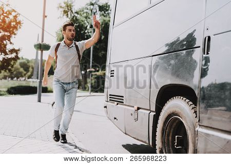 Young Handsome Tourist Almost Late For Bus. Man With Backpack Running After Tour Bus And Asking Bus 