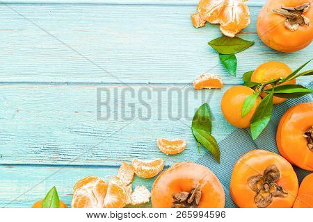 Healthy Diet Concept. Fresh Ripe Persimmons And Tangerines On Blue Wooden Background Top View Flt La