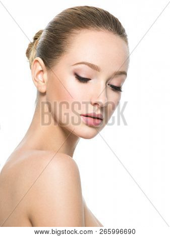 Beautiful face of young caucasian woman with perfect health fresh skin  - isolated on white.  Skin care concept. Female loooks down