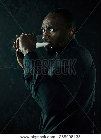 Healthy Young African Man Holging Cup Of Milk On A Bllack Studio Background.