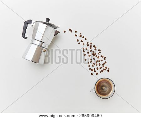 Italian coffee maker and fresh coffee beans coffee beans in the form of a drink stream on a white background with copy space. Concept of morning breakfast. Top view.