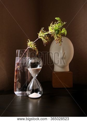 Still Life With Flowering Spring Twig Of Ash-tree With Young Leaves In A Glass Vase And Vintage Sand