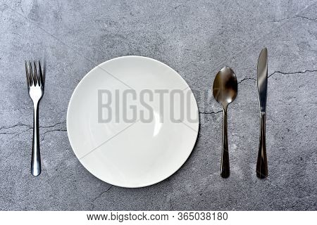 Top View Of Empty Plate Spoon Fork And Knife On Dark Color Background. Concept Of A Restaurant Bistr