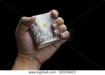 Man's Hand Holding Money Thailand's Baht Or Thai Banknote With In Hand On Black Background. Concept 