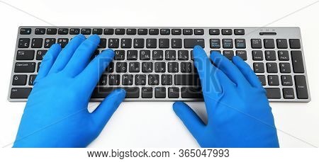 A Man In Blue Rubber Gloves Is Typing On The Keyboard. Disinfection In Public Places, The Fight Agai