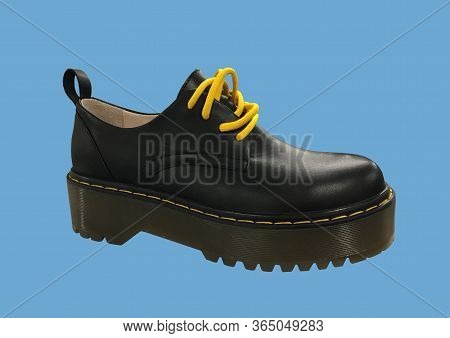 Black Leather Platform Shoes Isolated On Blue Background. Classic Shoes On A High Black Tractor Plat