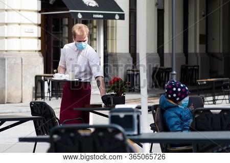 Vilnius, Lithuania - April 30 2020: Waiter With A Mask Disinfects The Table Of An Outdoor Bar, Café 