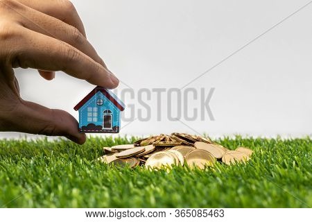Hand Hold A Home Model Put On The Stack Coin With Growing. Savings Money For Buy House And Loan To B