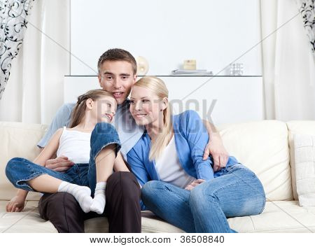 Oturma odasında beyaz kanepede oturan çekirdek aile gülmek