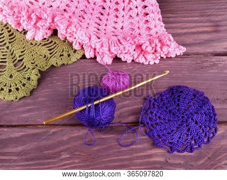 Crochet And A Skeins Of Dark Blue And Pink  Yarn, Top View On A Dark Wooden Background, In The Backg