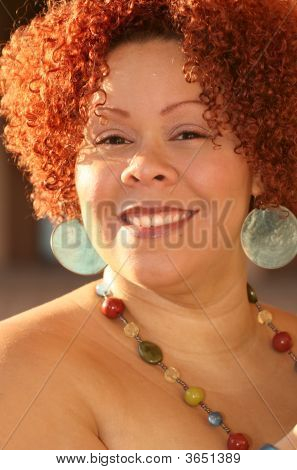 Mujer con cabello rizado rojo y joyas brillantes