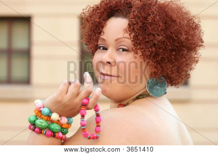 Mujer con cabello rizado rojo y joyas brillantes