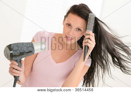 打撃は乾燥ラウンド ヘアブラシを使用して長い髪ブルネットの女性