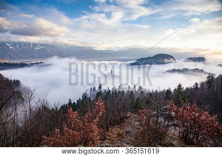 amazing panorama of Lake Bled Blejsko Jezero on a foggy morning with the Pilgrimage Church of the Assumption of Maria on a small island and Bled Castle and Julian Alps in backgroud