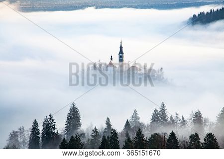 amazing panorama of Lake Bled Blejsko Jezero on a foggy morning with the Pilgrimage Church of the Assumption of Maria on a small island and Bled Castle and Julian Alps in backgroud