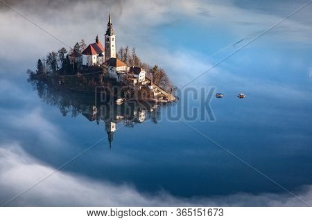 amazing panorama of Lake Bled Blejsko Jezero on a foggy morning with the Pilgrimage Church of the Assumption of Maria on a small island and Bled Castle and Julian Alps in backgroud