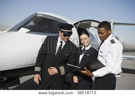 飛行機 airfie でバック グラウンドでレポートを議論する多民族の客室乗務員メンバー