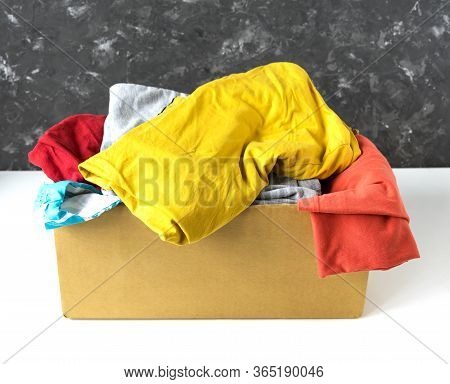 Clothes In A Cardboard Box. Seasonal Clothing For Shipping Or Donation. Close Up View.
