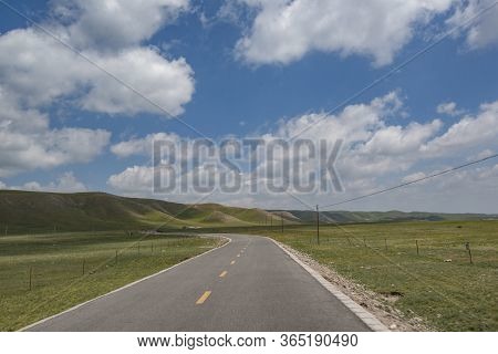 A Road Passing Through The Grasslands Of Qilian Mountains In The Sun