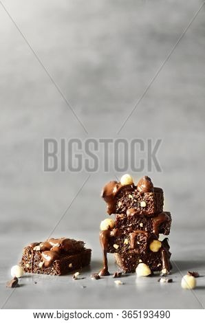 Stack Of A Brownie Pieces With Hazelnut On A Grey Table With Gray Background.