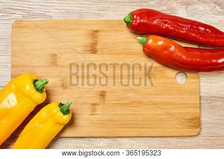 Still Life With Yellow And Red Pods Of Sweet Pepper On A Cutting Board