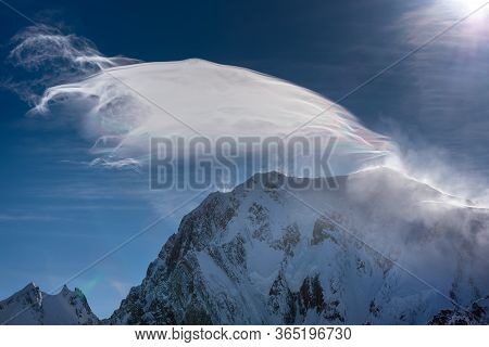 Strong Wind Blows The Snow Over A Mountain Top Creating A Strange Looking Cloud Iridescent In The Su