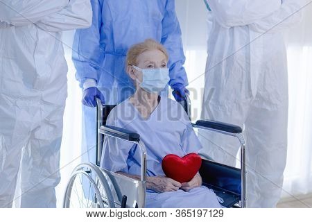 Old Woman Patient Hold Mini Heart On A Wheelchair With Background Of The Medical Team Thumbs Up Afte