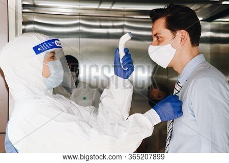 Social Distance Concept. Officer Wearing A Respirator Mask To Use Infrared Forehead Thermometer To C