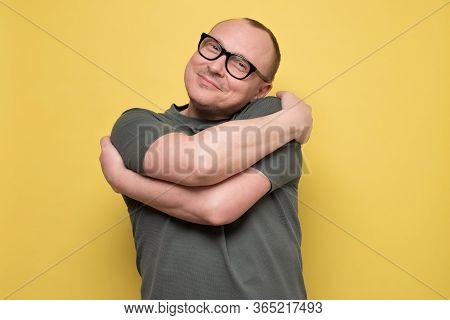 Man Smiling With Pleasure Embracing Himself, Keeping Arms Around His Shoulders