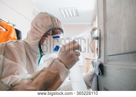 Coronavirus Pandemic. A Disinfector In A Protective Suit And Mask Sprays Disinfectants In House Or O