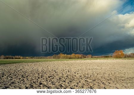 Huge Dark Hail Cloud Over The Plowed Field, View On A Spring Sunny Day