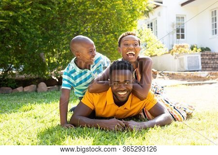 African American woman spending time with her partner and their son, lying on a lawn in the garden. Social distancing and self isolation in quarantine lockdown.