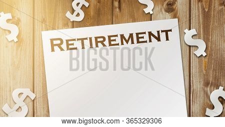 Word Retirement On A Copybook Page And Paper Dollar Signs Around On Wooden Table. The Concept Of Suc