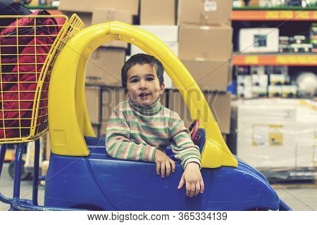The Boy 4 Years In A Striped Jacket Is Sitting In A Childrens Typewriter In A Construction Shop. Ton