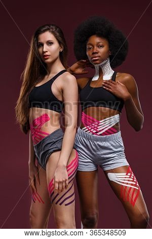 Kinesiology Taping. Two Young Female Athletes On Red Background With Kinesiology Tape On Neck, Shoul