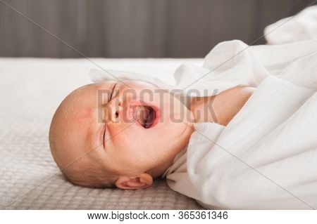 Newborn On The Bed. Crying, Screaming Baby Close Up And Copy Space. Baby Smile And Colic In Newborns