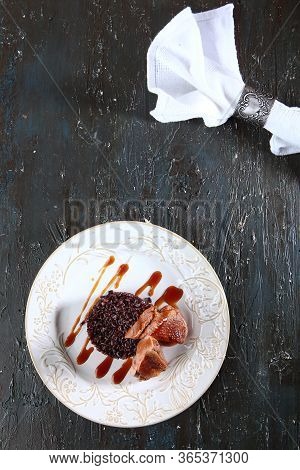 Duck With Brown Rice On A White Plate. The White Napkin Is Secured With A Vintage Metal Ring. Photo 