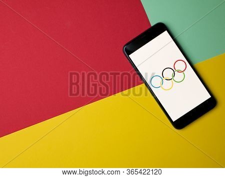 Usa - May, 2020 Olympic Games Logo On Iphone Screen On Colored Paper Background. Copy Space. Olympic