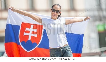 Beautiful Young Woman Holds A Flag Of Slovakia Oudoors On A Sunny Day, Wearing Sunglasses.