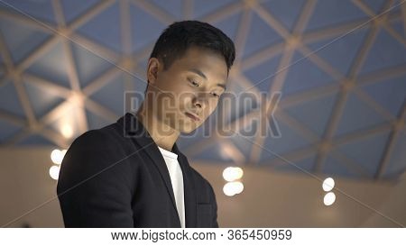 Handheld Portrait Shot Of Young Asian Man Dressed In Jacket And White Shirt Searching For Informatio