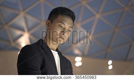 Handheld Portrait Shot Of Young Asian Man Dressed In Jacket And White Shirt Searching For Informatio
