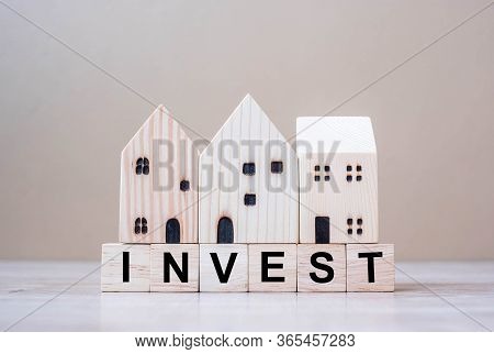 Invest Cube Blocks With Wooden House Model On Table Background. Coronavirus Pandemic, Business, Risk
