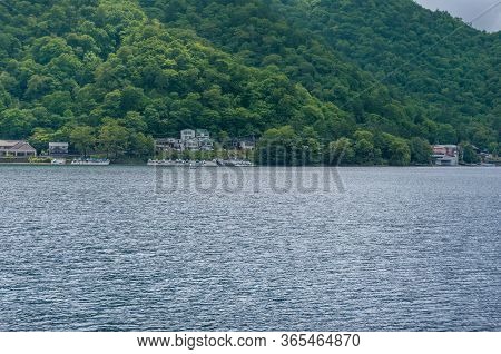 Lake Chuzenji And Mountains Landscape With Waterfront Buildings On The Backgorund