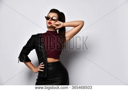 Portrait Of Brunette Woman In Red Sunglasses, Jewelry, Top And Black Leather Skirt And Jacket Posing