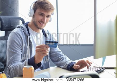 Portrait Of A Young Man Holds And Using Credit Card For Game Money Top Up.