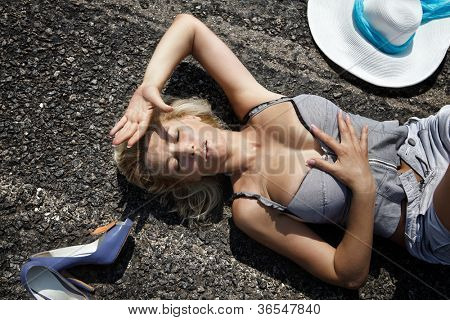 Donna sdraiata su una strada nel deserto schermatura sole con la mano