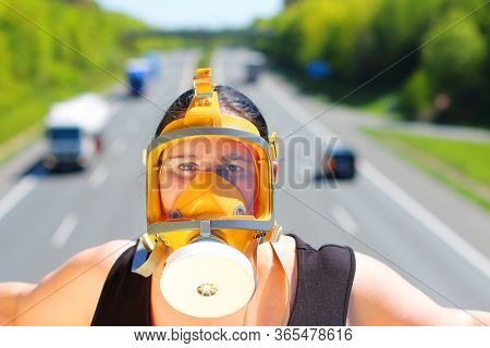 Woman with fullface respirator over street traffic. Health hazard from air pollution, allergy or infection. Protective clothing in action.